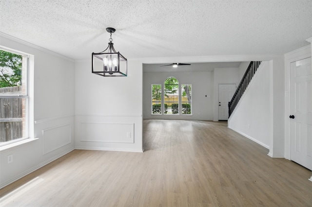 interior space with stairs, a textured ceiling, a healthy amount of sunlight, and light wood finished floors