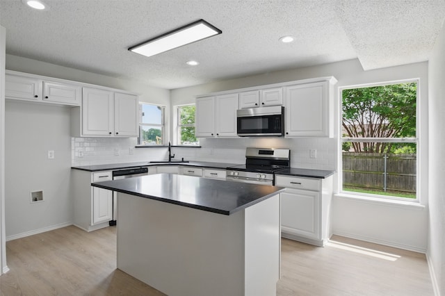 kitchen with dark countertops, appliances with stainless steel finishes, decorative backsplash, and a sink
