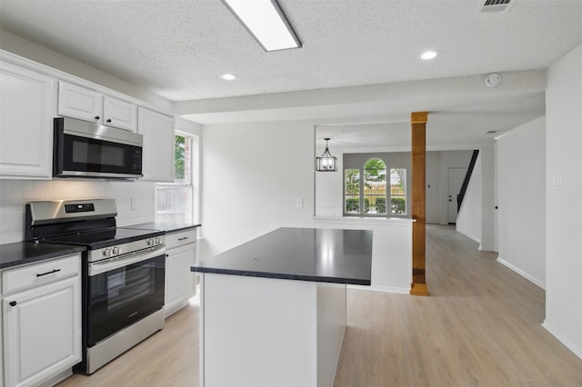 kitchen featuring light wood-style floors, appliances with stainless steel finishes, backsplash, and dark countertops