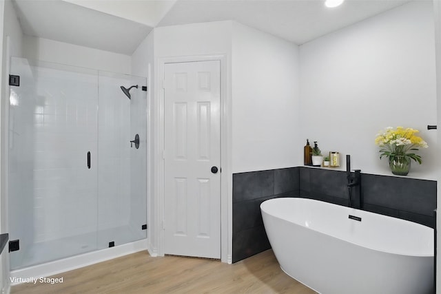 bathroom featuring a stall shower, a freestanding bath, and wood finished floors