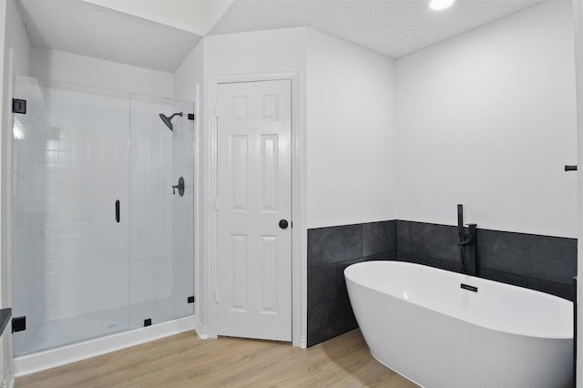 bathroom featuring a stall shower, a freestanding tub, and wood finished floors