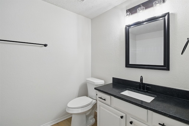 bathroom with vanity, toilet, a textured ceiling, baseboards, and wood finished floors