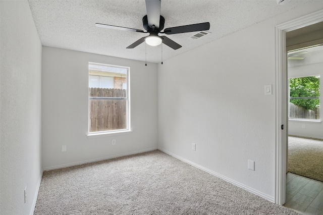 carpeted empty room featuring baseboards, a ceiling fan, a textured ceiling, and visible vents