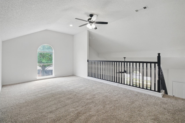 additional living space featuring carpet flooring, ceiling fan, visible vents, a textured ceiling, and vaulted ceiling
