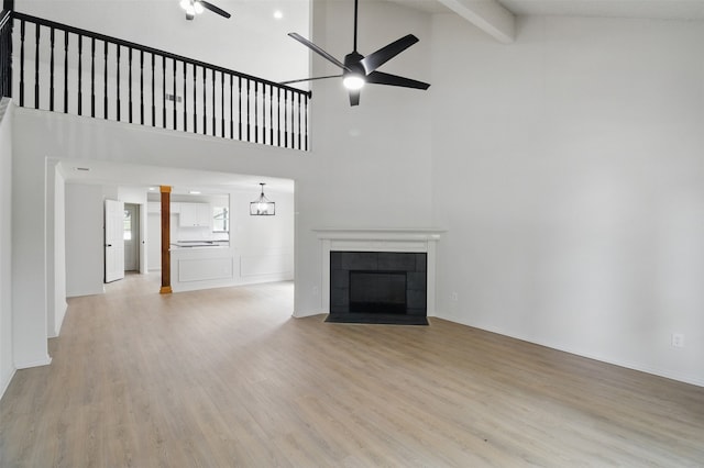 unfurnished living room with ceiling fan, a fireplace, light wood-style floors, high vaulted ceiling, and beamed ceiling