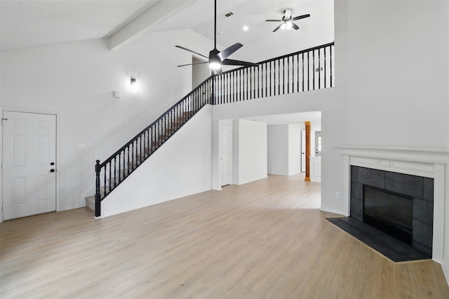 unfurnished living room with stairway, high vaulted ceiling, ceiling fan, and wood finished floors