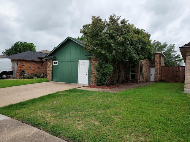 exterior space featuring brick siding, a front lawn, fence, and concrete driveway