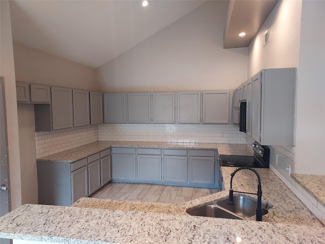 kitchen featuring appliances with stainless steel finishes, gray cabinetry, a sink, and tasteful backsplash