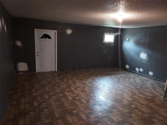 unfurnished room featuring brick patterned floor and a textured ceiling
