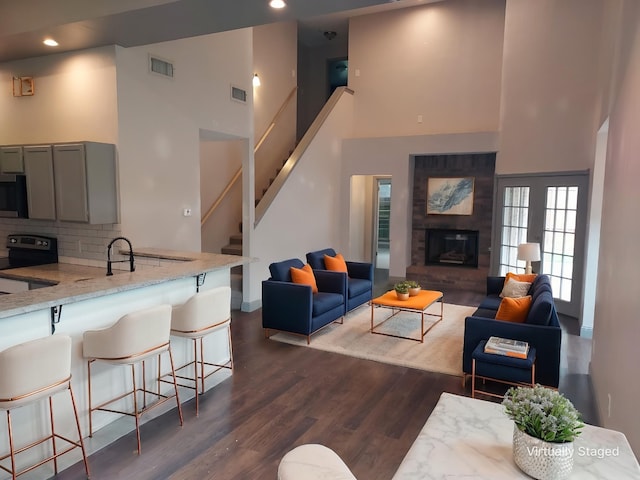 living area featuring stairway, a towering ceiling, dark wood-style flooring, and visible vents