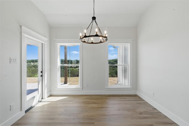 unfurnished dining area with an inviting chandelier, baseboards, light wood-style floors, and a healthy amount of sunlight