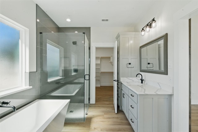 bathroom featuring wood finished floors, a stall shower, visible vents, and vanity