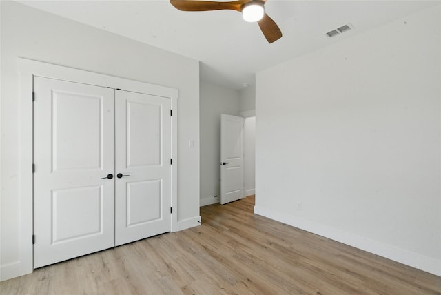 unfurnished bedroom featuring ceiling fan, light wood-style floors, baseboards, visible vents, and a closet
