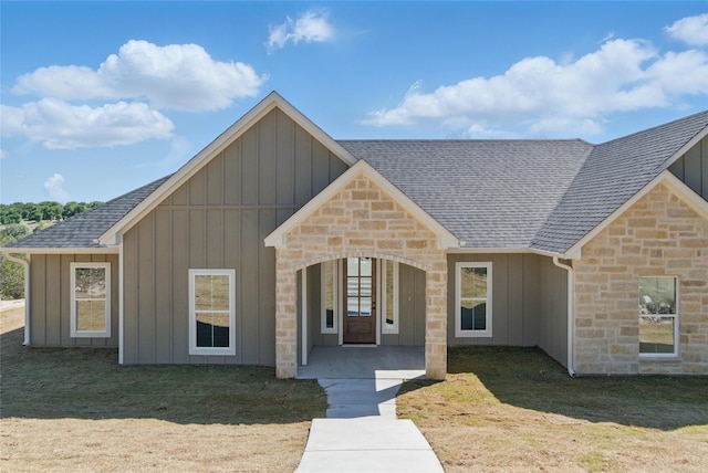 view of front facade with board and batten siding, roof with shingles, and stone siding