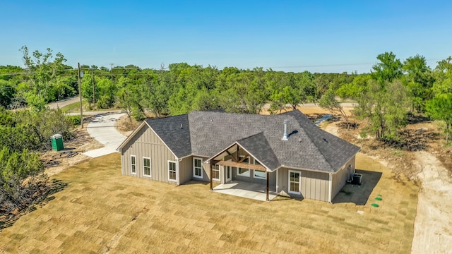 rear view of house featuring roof with shingles, board and batten siding, and a patio area