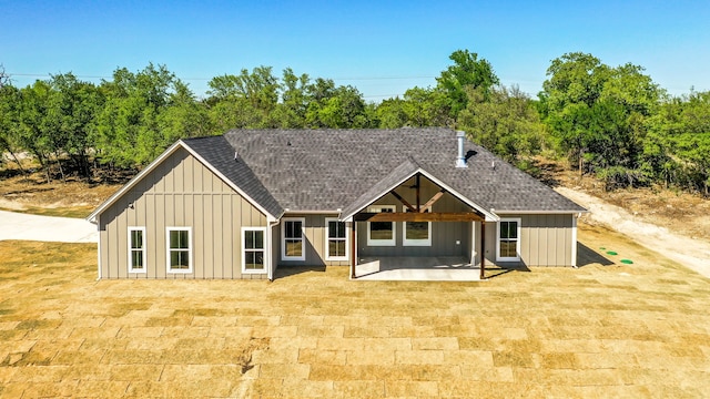 back of property with a patio, a shingled roof, and board and batten siding