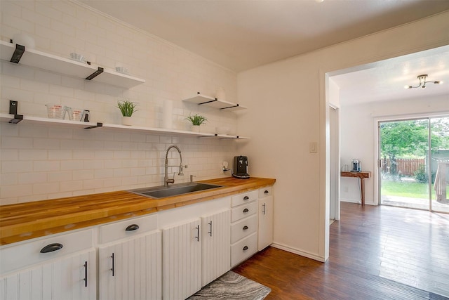 kitchen with decorative backsplash, open shelves, butcher block counters, and a sink
