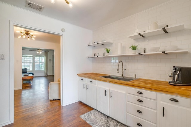 kitchen featuring a sink, wood counters, open shelves, and visible vents