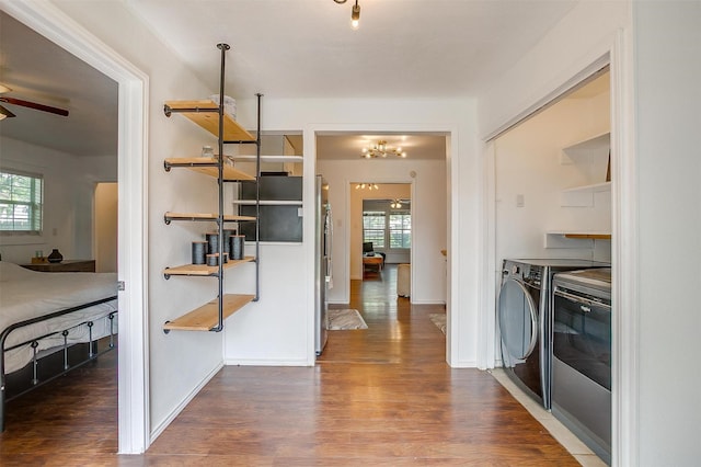 hall featuring independent washer and dryer, baseboards, plenty of natural light, and wood finished floors