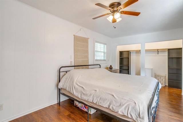 bedroom featuring a ceiling fan, two closets, and wood finished floors