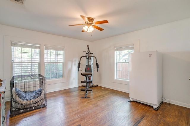 exercise area featuring baseboards, a ceiling fan, and wood finished floors