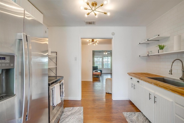 kitchen featuring dark wood-style flooring, a notable chandelier, appliances with stainless steel finishes, a sink, and backsplash