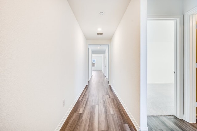 hallway featuring dark wood-style flooring, baseboards, and visible vents