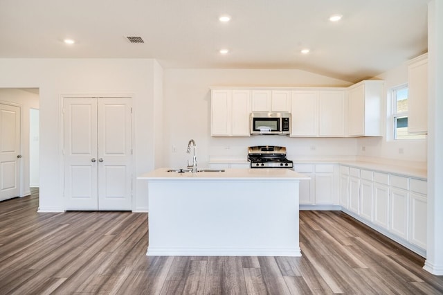 kitchen with a sink, appliances with stainless steel finishes, a kitchen island with sink, and wood finished floors
