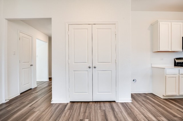 kitchen with baseboards, white cabinetry, and wood finished floors