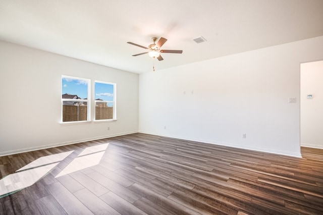 unfurnished room with dark wood-style flooring, ceiling fan, visible vents, and baseboards