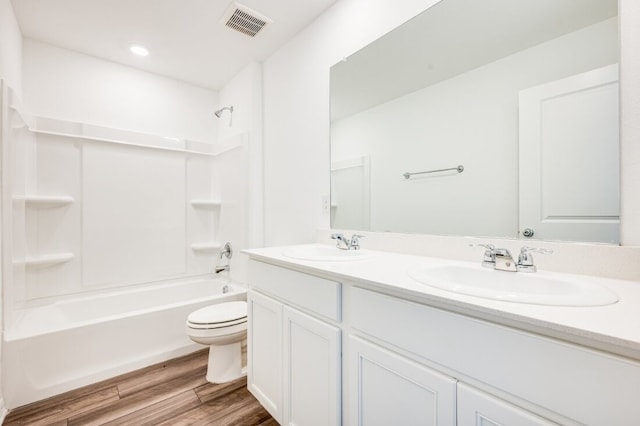 bathroom with a sink, double vanity, toilet, wood finished floors, and visible vents