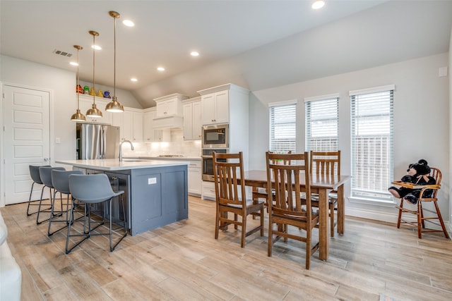 kitchen featuring appliances with stainless steel finishes, tasteful backsplash, light countertops, light wood-type flooring, and visible vents
