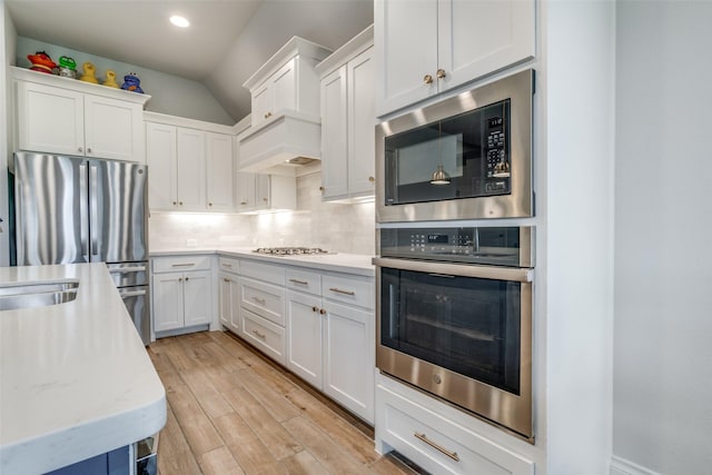kitchen with decorative backsplash, light wood-style flooring, white cabinets, and stainless steel appliances