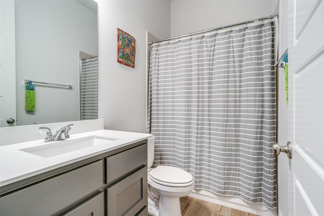 bathroom featuring toilet, curtained shower, wood finished floors, and vanity