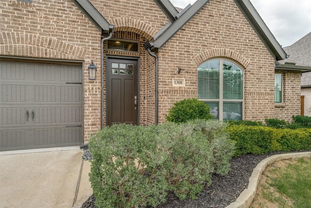 property entrance featuring brick siding, an attached garage, and roof with shingles