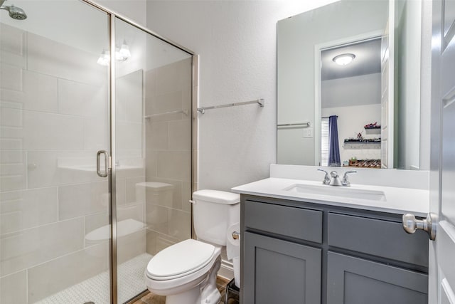 bathroom featuring vanity, a textured wall, toilet, and a shower stall