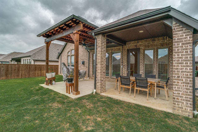 rear view of house with a patio, fence, a yard, and brick siding