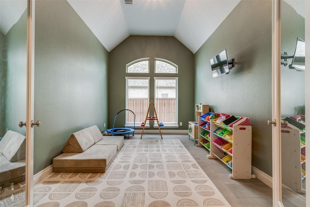 playroom featuring a textured wall, vaulted ceiling, and french doors