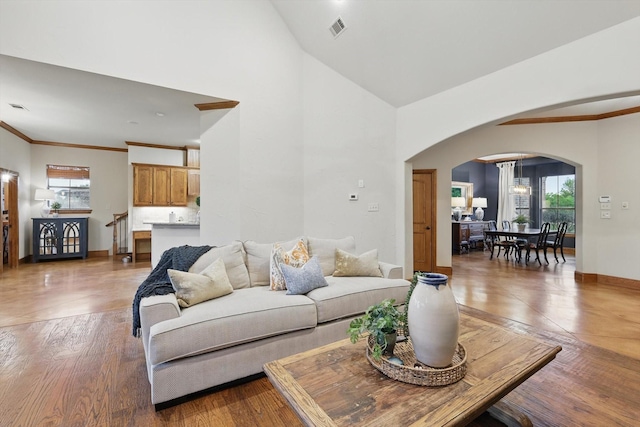 living room with arched walkways, baseboards, plenty of natural light, and wood finished floors