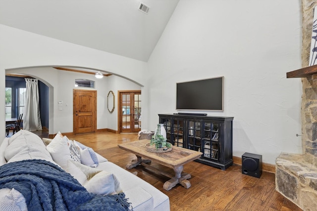 living room featuring visible vents, arched walkways, baseboards, and wood finished floors