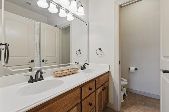 bathroom with a sink, baseboards, toilet, and double vanity