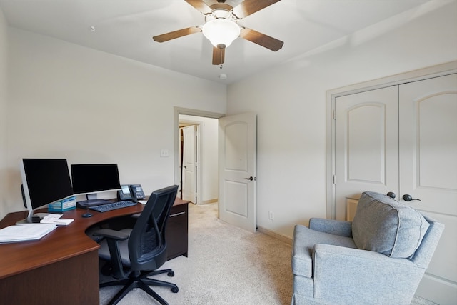home office featuring a ceiling fan, baseboards, and light carpet
