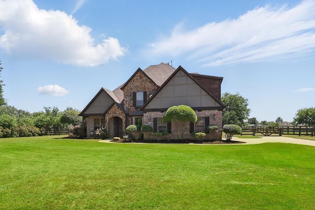 view of front of home featuring brick siding, stone siding, fence, and a front yard