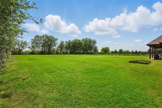 view of yard with fence and a rural view