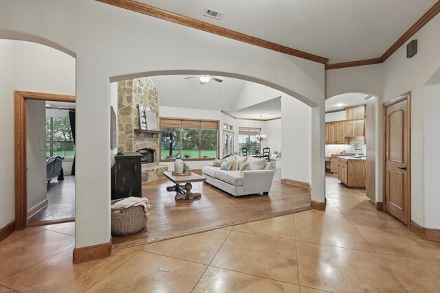 living room with crown molding, ceiling fan, arched walkways, light tile patterned floors, and visible vents