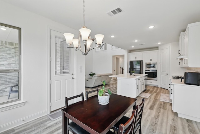 dining room featuring light wood-style floors, an inviting chandelier, recessed lighting, and visible vents