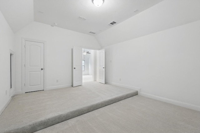 unfurnished bedroom featuring visible vents, vaulted ceiling, and light carpet