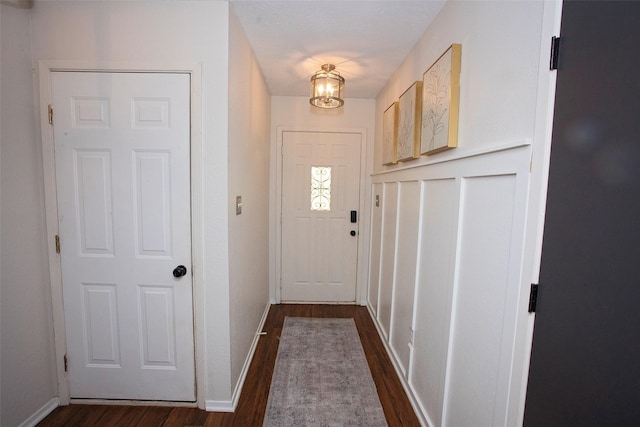 doorway with baseboards and dark wood-type flooring