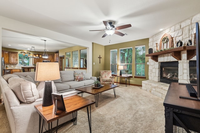 living room featuring carpet floors, ceiling fan, a stone fireplace, and baseboards