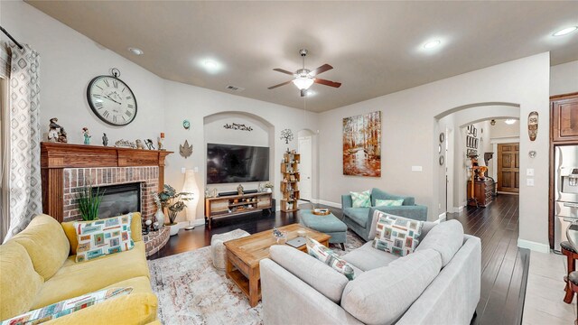 living room with arched walkways, a ceiling fan, wood finished floors, and visible vents
